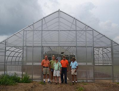 Fine produce — and flowers, too. Ira Bezoza, Darcy Hutzenlaub, John Malafronte, Bruce Warr, and Peter Garnham stood in the doorway to the East Hampton Food Pantry Farm’s recently added greenhouse. Left, young participants worked recently with Eliza Kellman, a summer intern at the farm’s herb garden.