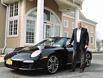 Michael J. Griffith, international lawyer and inspiration for a new television series, stood by his Porsche Carrera S, “which never leaves the Hamptons,” outside East Hampton Town Justice Court on Saturday.