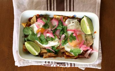 Salty and cheesy chilaquiles are an easy option using things most people have on hand. Here, they are made with tortilla chips, salsa, and cheese and topped with fried eggs and a garnish of lime and cilantro.