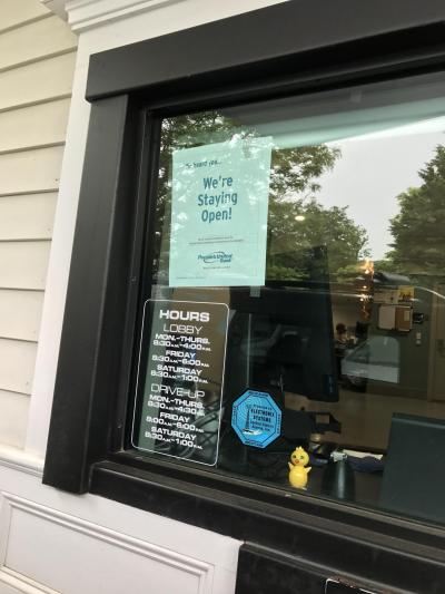 A sign at the drive-through window alerted customers that the bank will remain open. A sign at the drive-through window alerted customers that the bank will remain open.