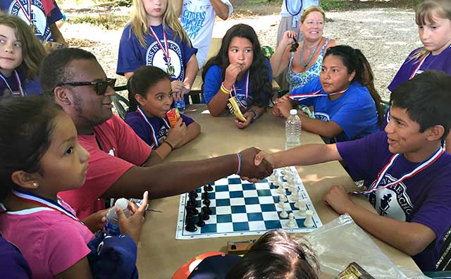 A handshake between Morgan Brown, left, and Alex Vanegas, right, symbolized the start of a championship chess game on Tuesday morning near the end of the first-ever Chess in the Schools tournament on Long Island at the LongHouse Reserve.