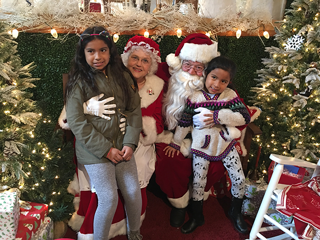 Mr. and Mrs. Claus (a.k.a. Bonnie and Stan Morlando) with 9-year-old Emely and 5-year-old Kailyn Urgiles at the Snow Village at Groundworks Landscaping in East Hampton. “I want a pony for Christmas,” Kailyn said.
