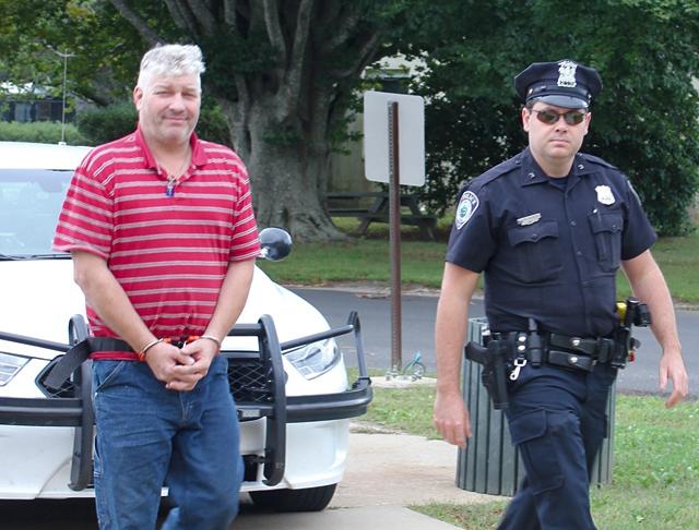 An East Hampton Town police officer led Martin Drew into Justice Court on Friday morning.