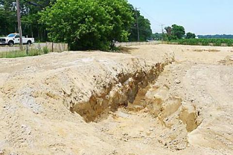 Work on a drainage basin being built by East Hampton Town was halted when Suffolk officials learned the work was being done on farmland over which the county owns development rights.