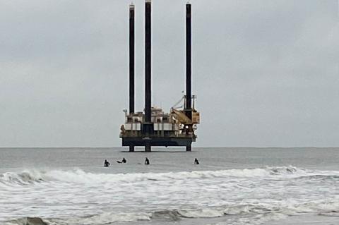 Surfers near Georgica Beach dwarfed by an exploratory driling rig taking sea-floor samples in preparation for a planned electric cable installation